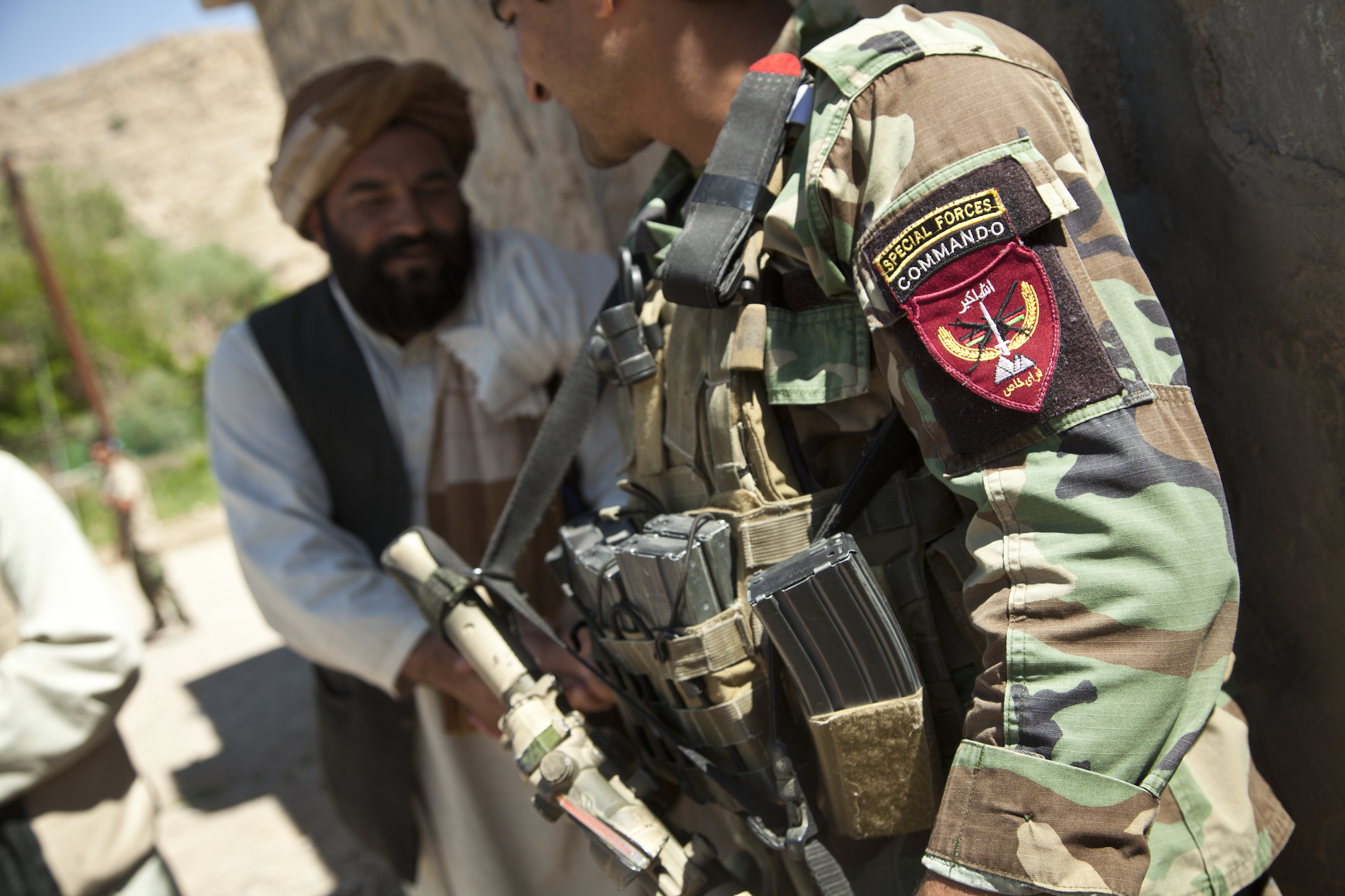 An Afghan National Army special forces soldier, right, talks with a potential Afghan Local Police candidate in Helmand province, Afghanistan