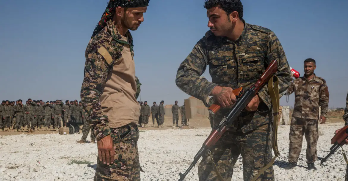 An instructor with the Syrian Democratic Forces observes a Syrian Arab trainee clear his rifle during small arms training in Northern Syria,