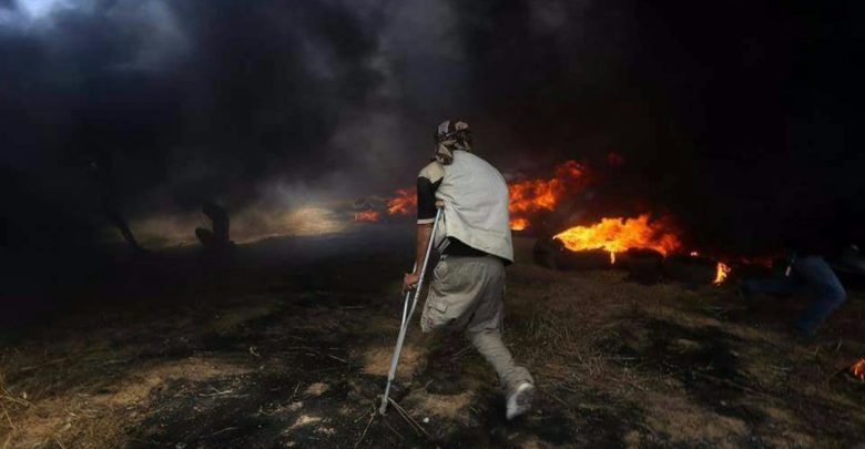 A Palestinian man in Gaza approaches a tire fire