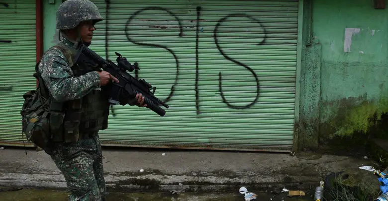 A Philippine Marine walks past graffiti during a patrol along a deserted street at the frontline in Marawi, on the southern island of Mindanao on July 22, 2017.