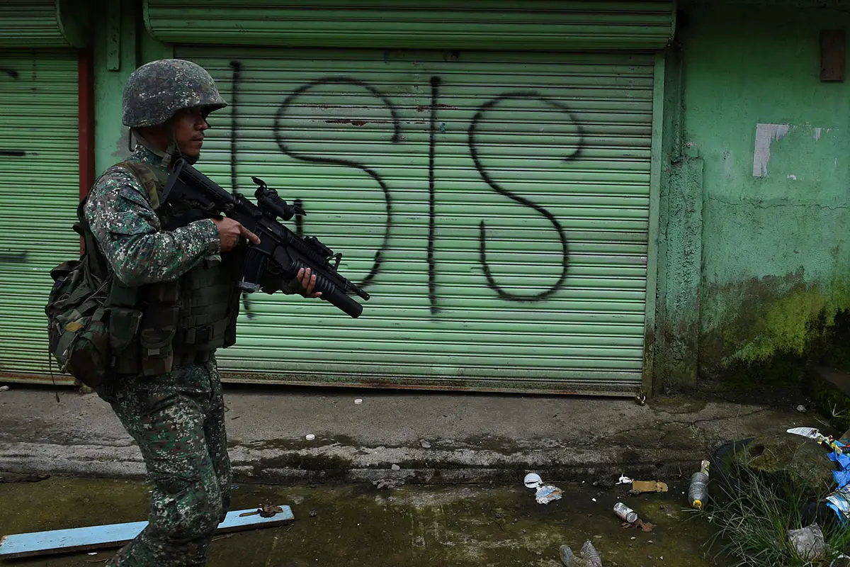 A Philippine Marine walks past graffiti during a patrol along a deserted street at the frontline in Marawi, on the southern island of Mindanao on July 22, 2017.