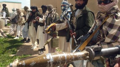 Taliban militants in a line holding guns and explosives