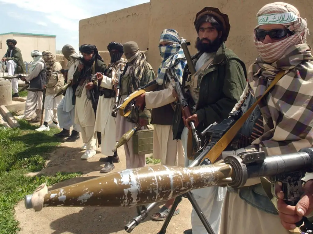 Taliban militants in a line holding guns and explosives