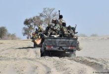 Nigerian soldiers traveling on the back of a pick-up truck.