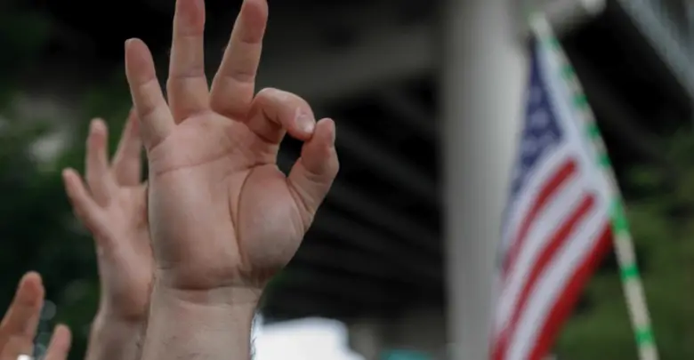 A demonstrator makes a hand gesture believed to have white supremacist connotations, Aug. 17, 2019, in Portland, Oregon, United States