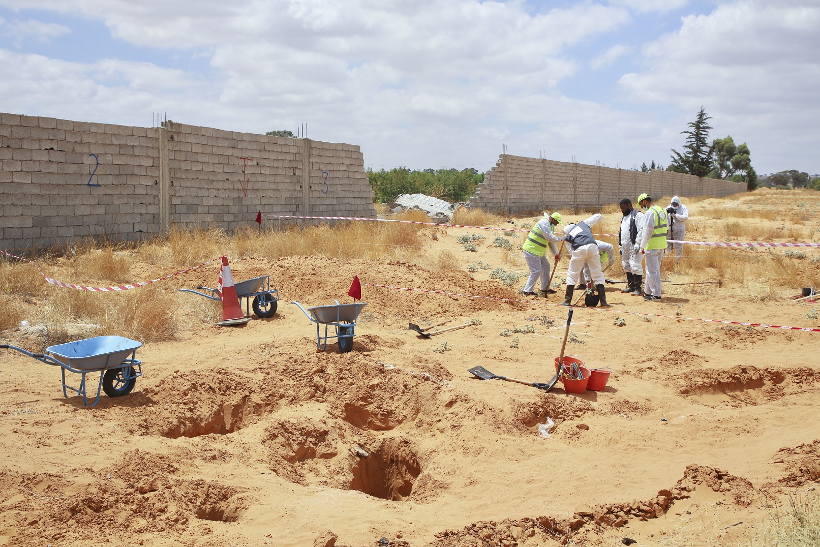 Libyan Ministry of Justice employees dig at the site of a suspected mass grave in Tarhouna, Libya on June 23, 2020.