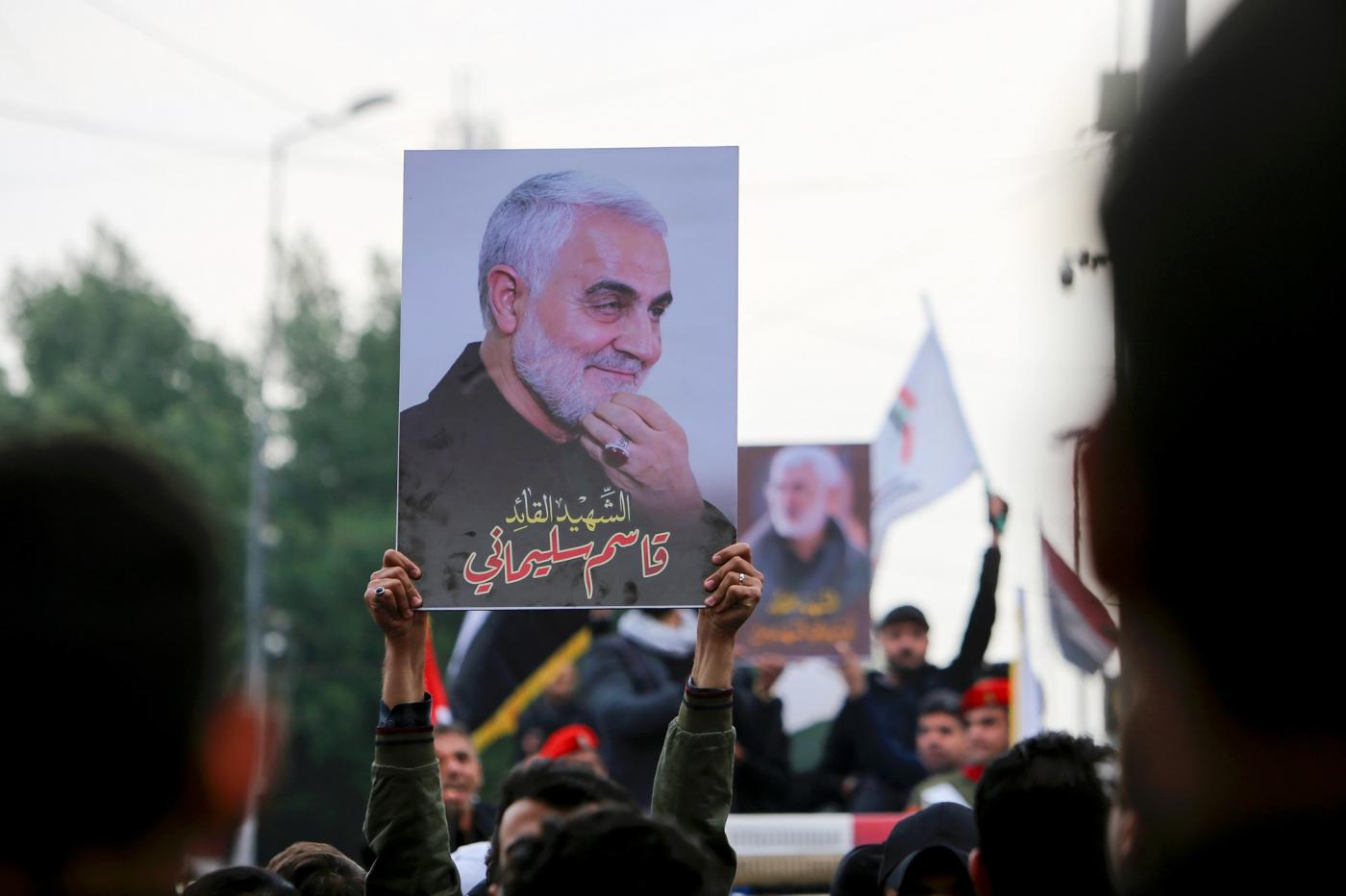 Mourners hold up pictures of General Qassem Soleimani at his funeral in January 2020.
