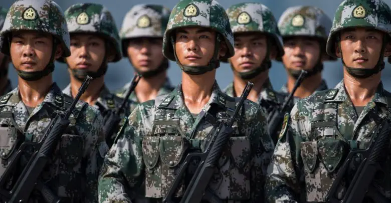 Chinese soldiers look on.