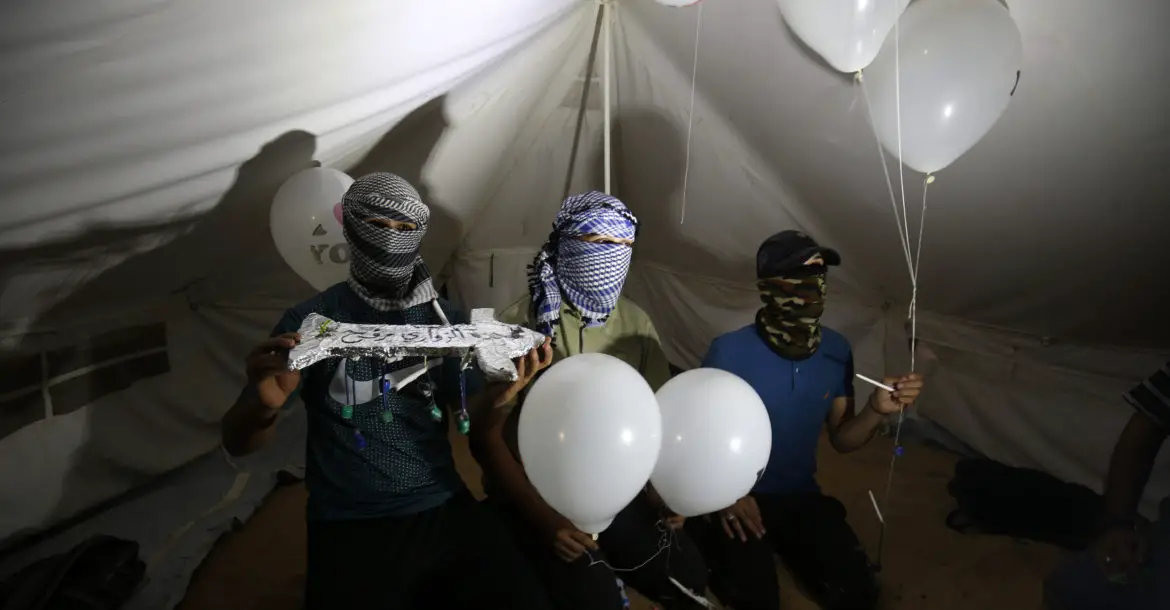 asked Palestinians calling themselves the "night confusion units" hold incendiary devices attached to balloons to be flown into Israel, near the Gaza-Israel border east of Rafah, September 2018.