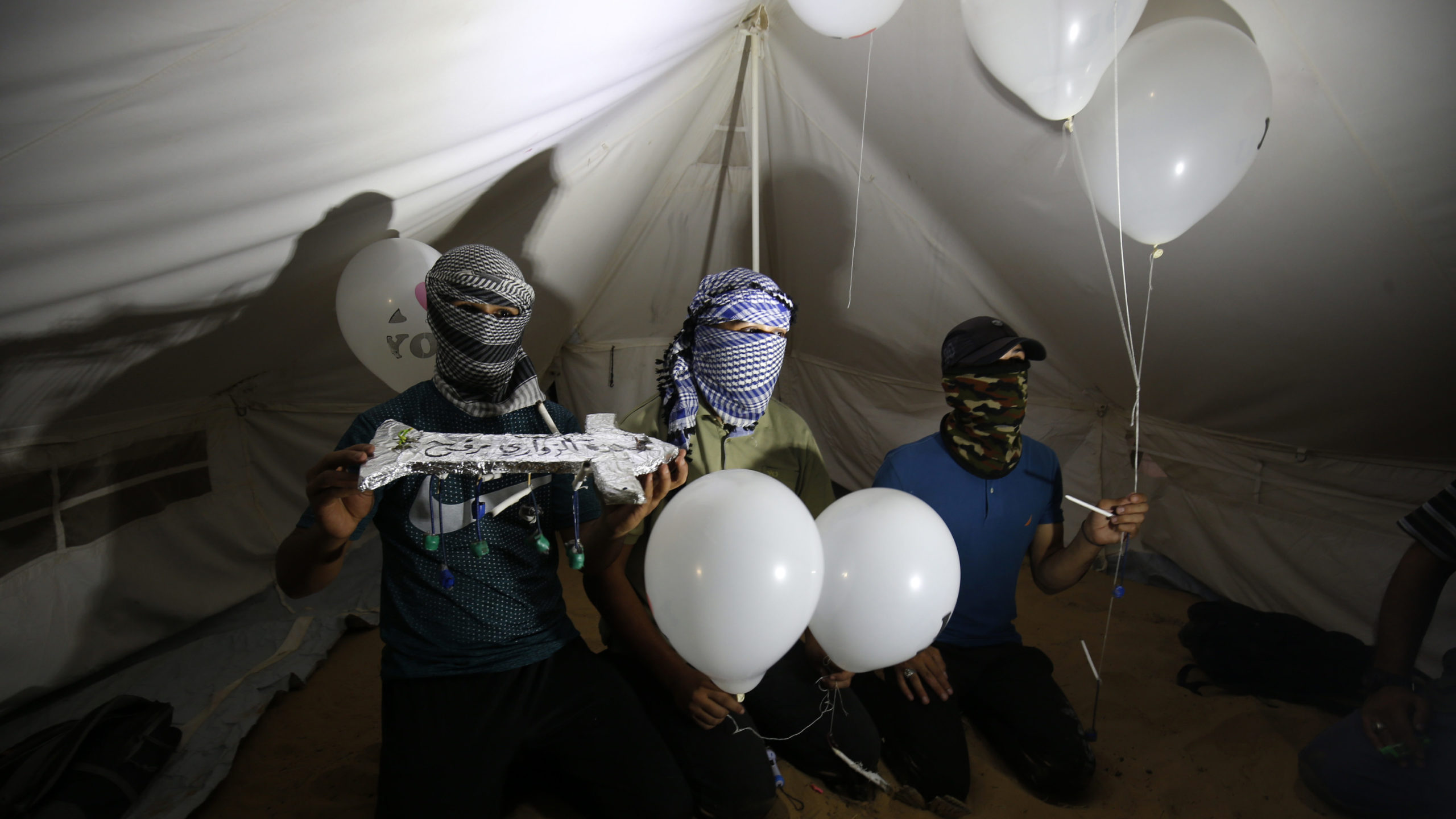asked Palestinians calling themselves the "night confusion units" hold incendiary devices attached to balloons to be flown into Israel, near the Gaza-Israel border east of Rafah, September 2018. 