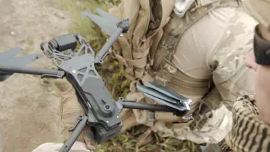 A man in defense outfit holding a Skydio X2 drone.