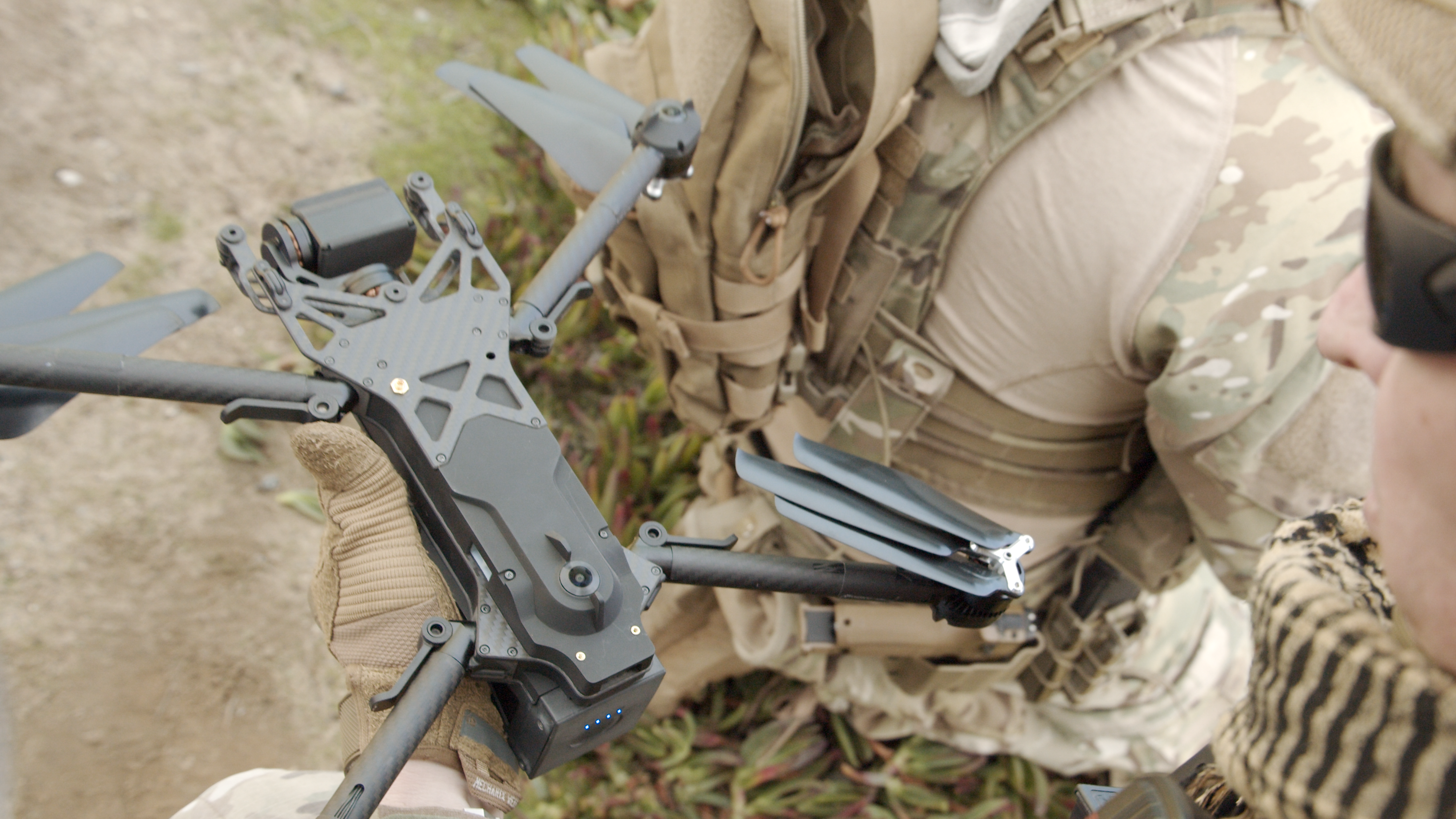 A man in defense outfit holding a Skydio X2 drone.