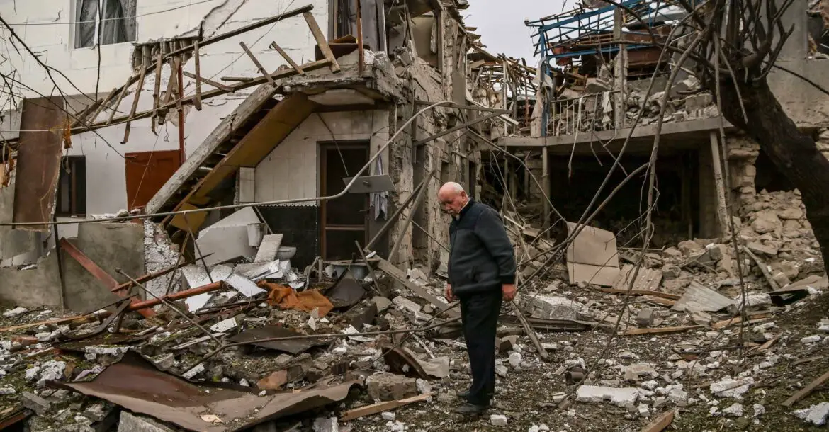 An elderly man stands in front of a destroyed house after shelling in the occupied Nagorno-Karabakh region's main city of Stepanakert.