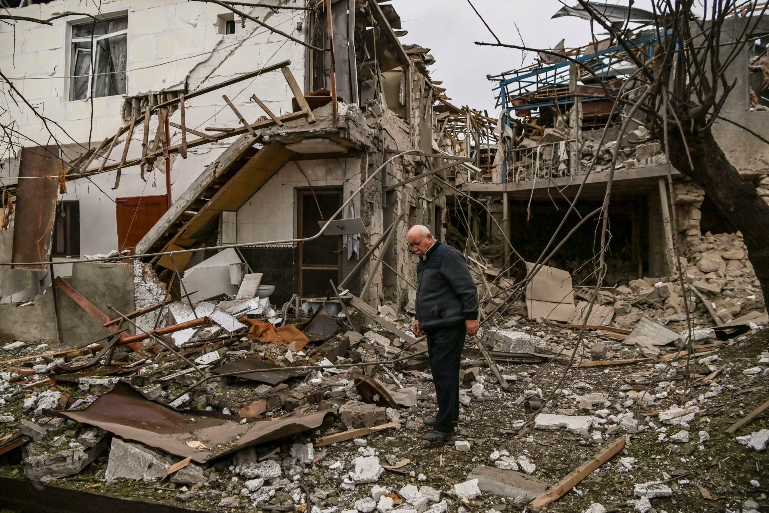 An elderly man stands in front of a destroyed house after shelling in the occupied Nagorno-Karabakh region's main city of Stepanakert.