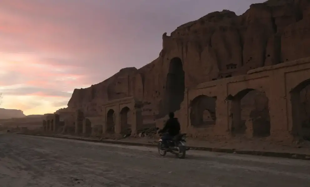 File: A man rides his motorbike during sunset in front of the empty seat of one of the two Buddha statues destroyed by the Taliban in 2001 in Bamiyan, on November 19, 2019