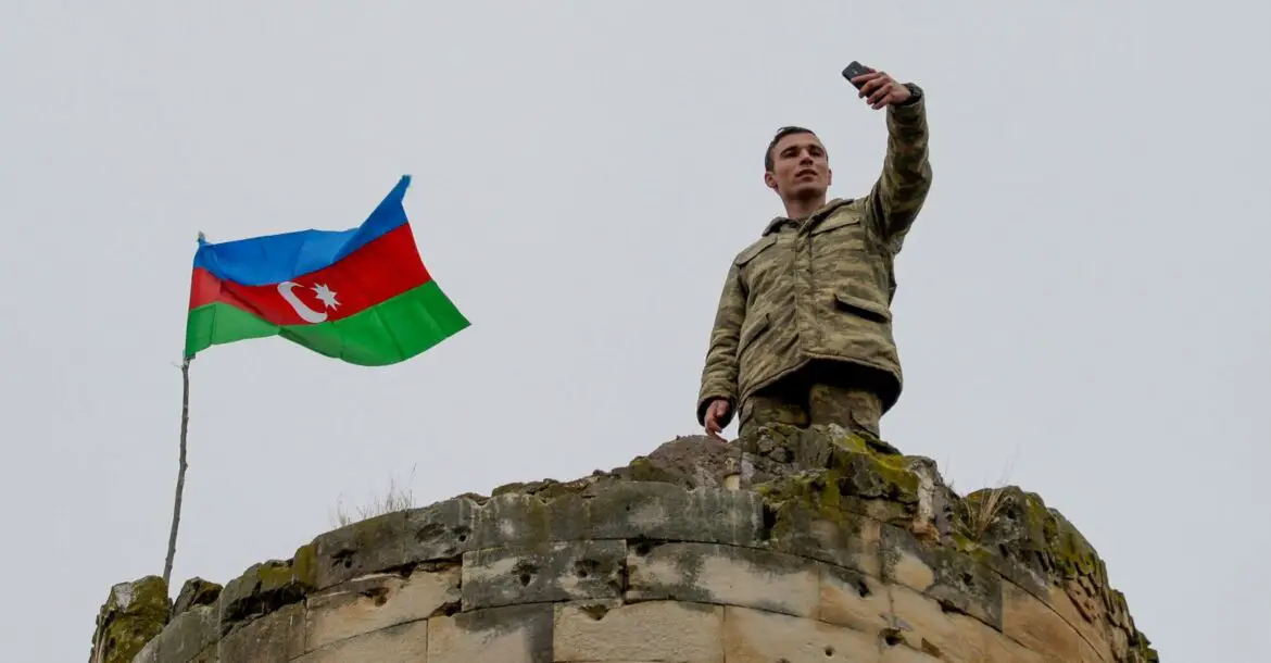 An Azerbaijani soldier takes a selfie with the national flag in Fuzuli, a liberated city, last November 26, 2020.