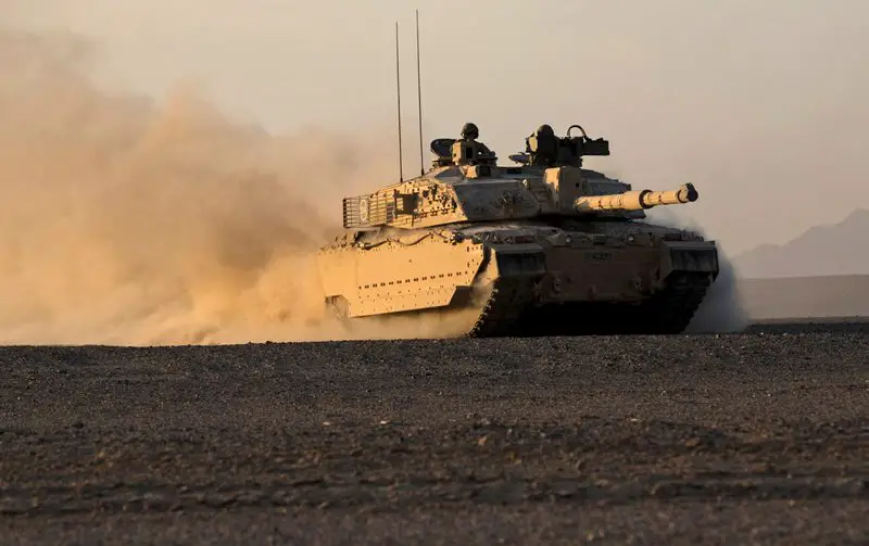 The British Challenger 2 MBT of the 1st Royal Tank Regiment glides effortlessly across soft sand with the low evening light of the Omani landscape glinting off the desert camouflage