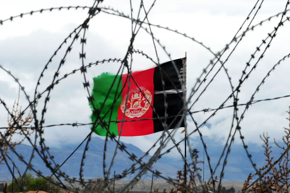 Afghan flag behind barbed wire.