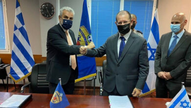 Israel Ministry of Defense official striking a pose concluding deal with Greek official