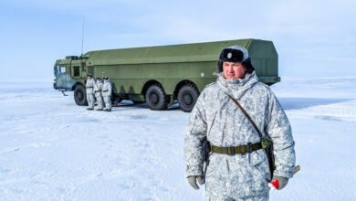 A Russian officer and soldiers stand next to a special military truck at the Russian northern military base on Kotelny island, beyond the Arctic Circle on April 3, 2019