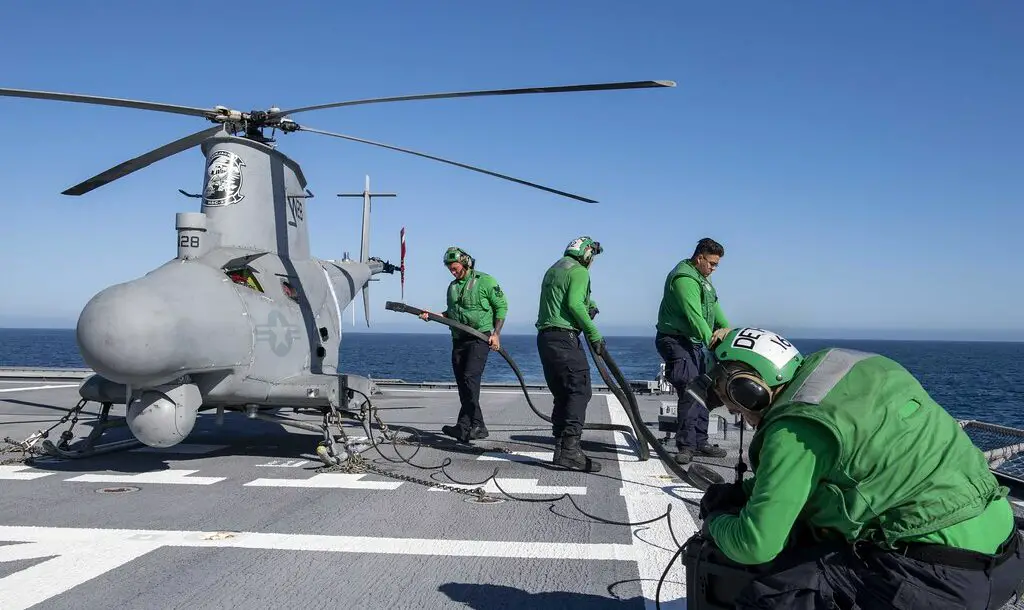 Sailors charge the battery of an MQ-8B Fire Scout unmanned aerial vehicle aboard Independence-variant littoral combat ship USS Charleston