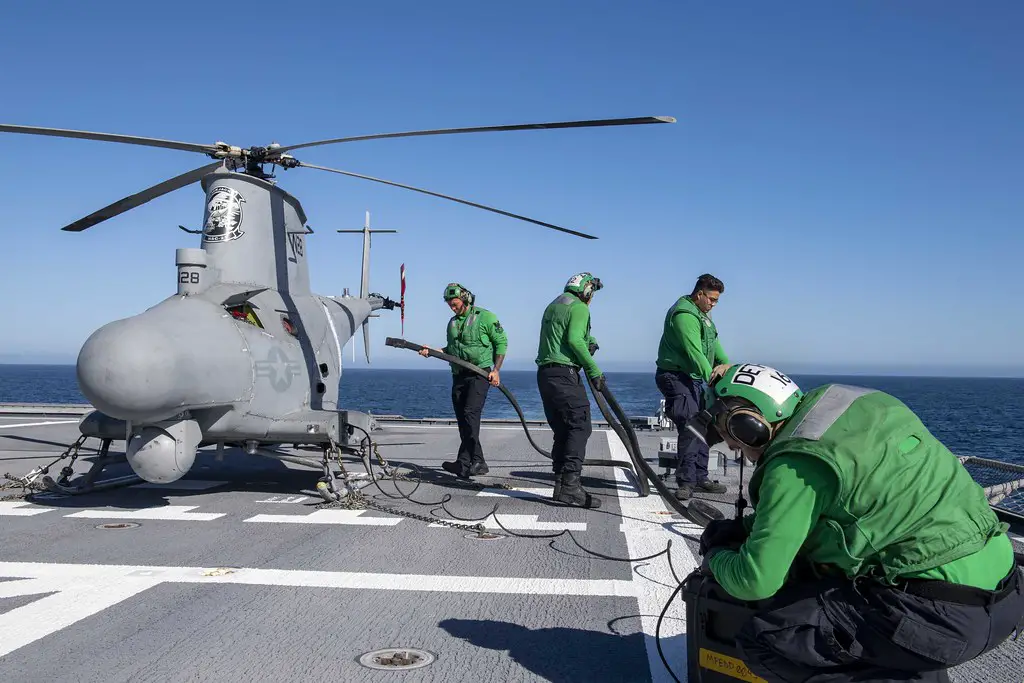 Sailors charge the battery of an MQ-8B Fire Scout unmanned aerial vehicle aboard Independence-variant littoral combat ship USS Charleston