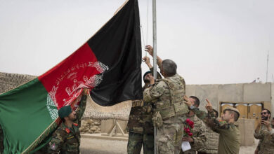This handout photograph taken on May 2, 2021 and released by Afghanistan's Ministry of Defense shows US soldiwrs and Afghan National Army (ANA) soldiers rising Afghanistan's national flag uring a handover ceremony to the Afghan National Army (ANA) army 215 Maiwand corps at Antonik camp in Helmand province.