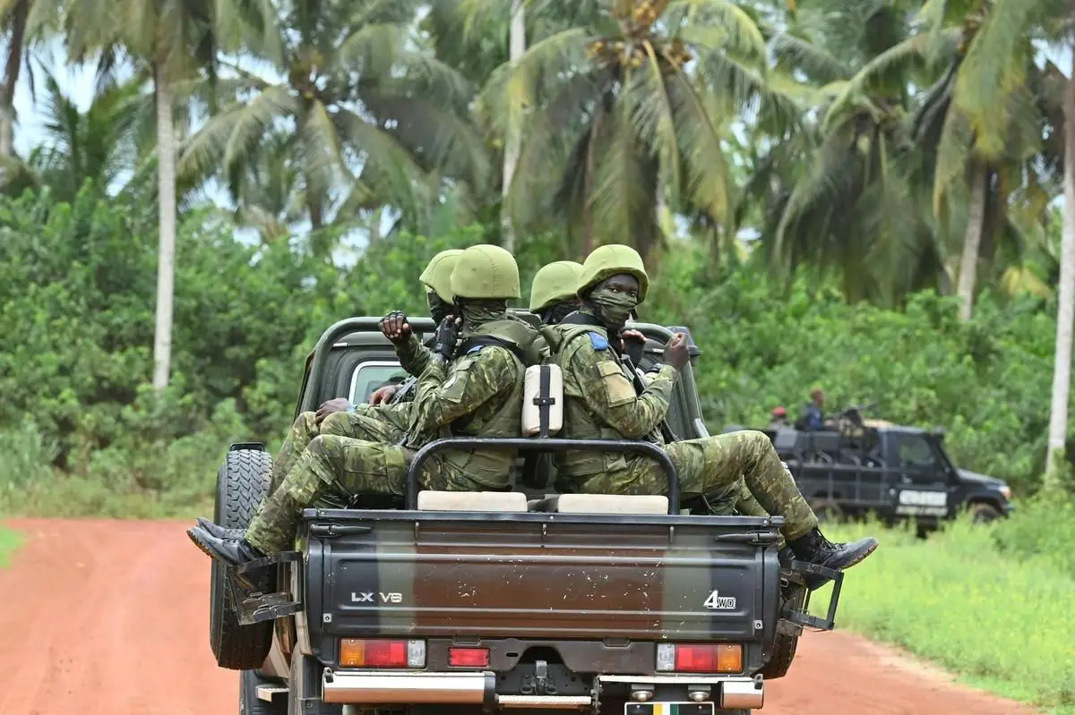 Ivorian soldiers drive on the back of a vehicle outside the International Academy for Combating Terrorism in Jacqueville in Ivory Coast on June 10, 2021