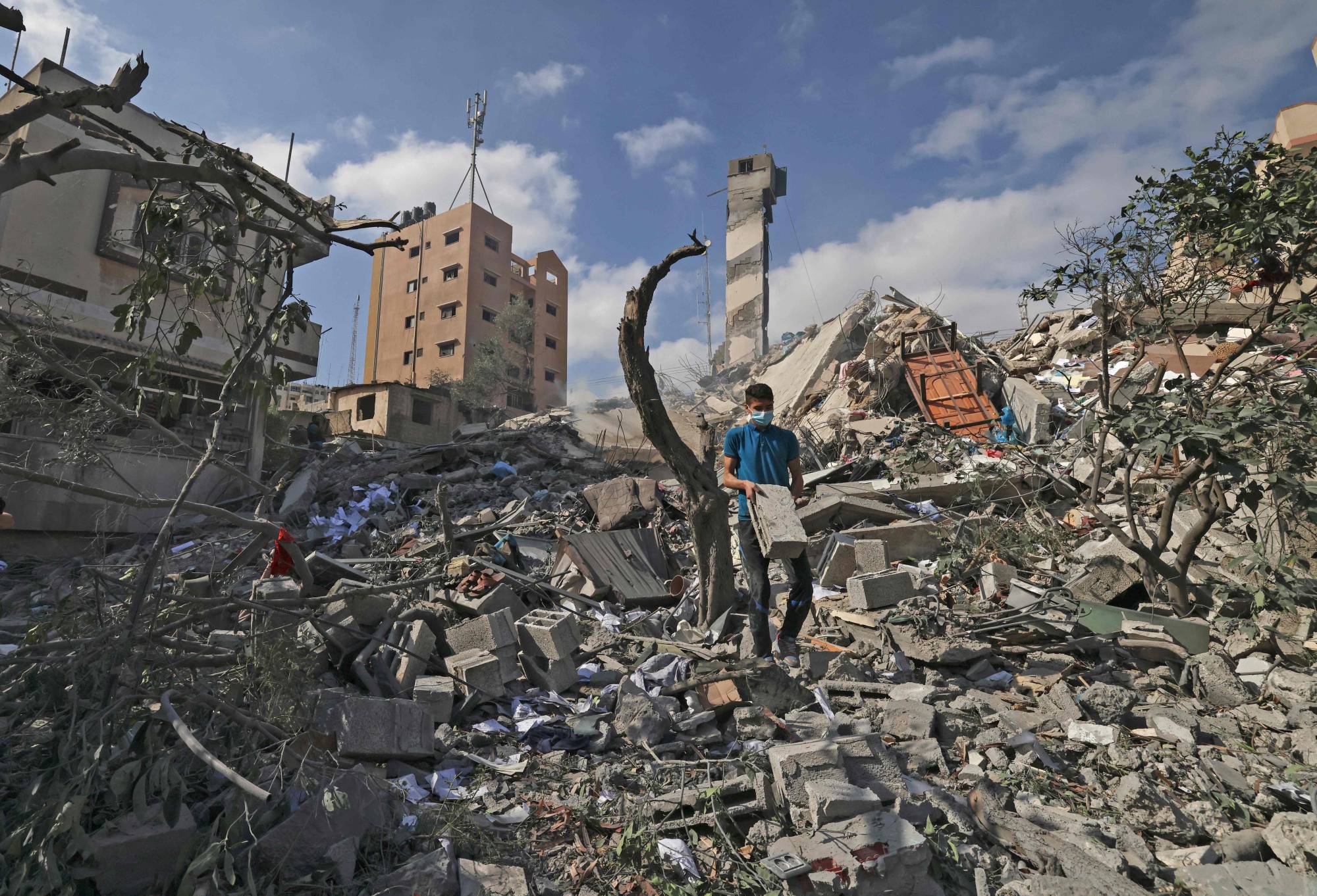 A Palestinian youth looks for salvageable items amid the rubble of the Kuhail building, which was destroyed in an early morning Israeli airstrike on Gaza City