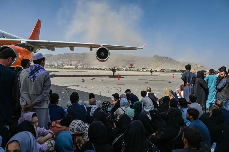Afghan people wait to leave the Kabul airport on August 16, 2021