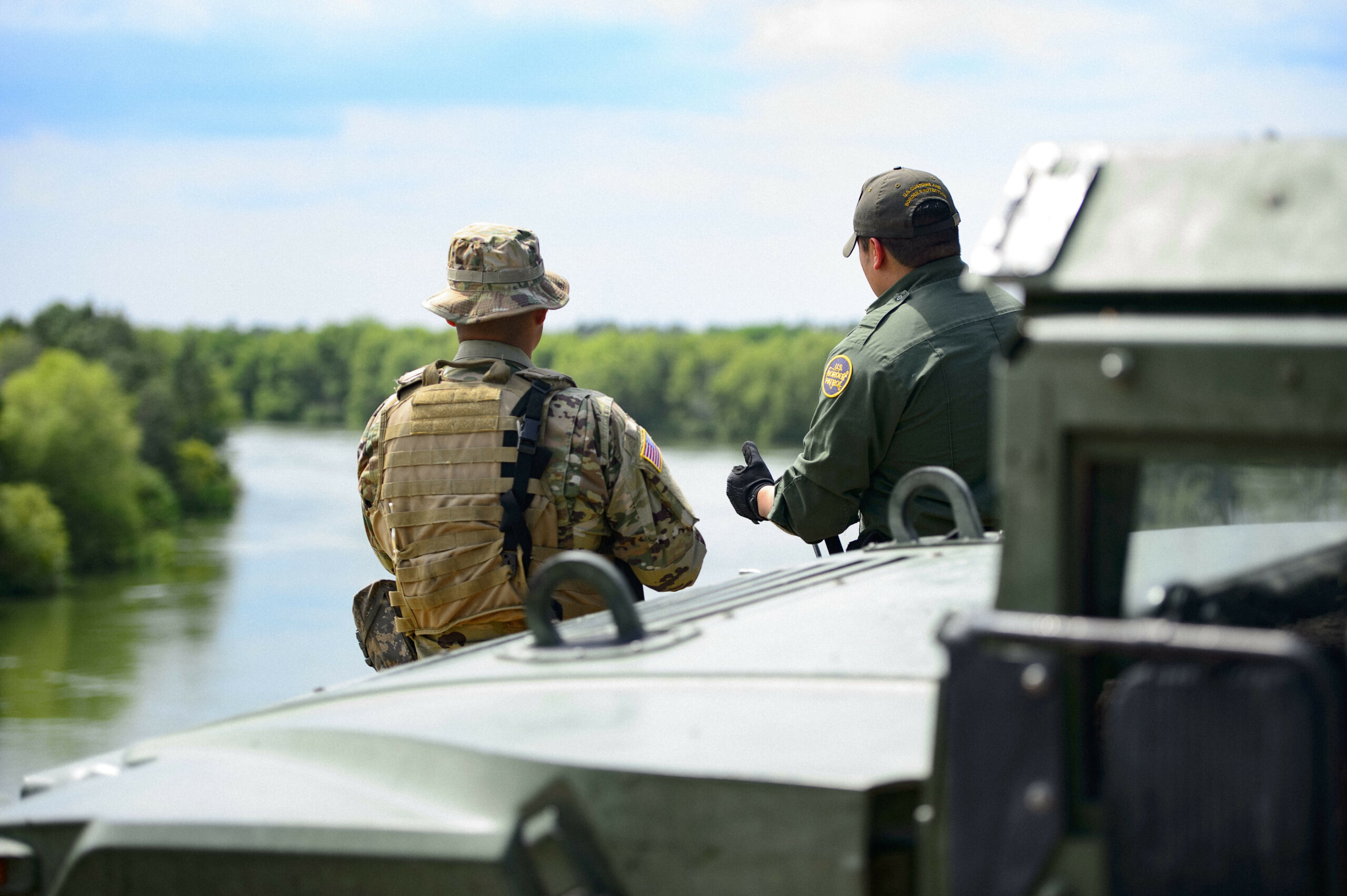 A Texas Guardsmen and a Customs and Border Patrol agent discuss the lay of the land on the shores of the Rio Grande River in Starr County, Texas.