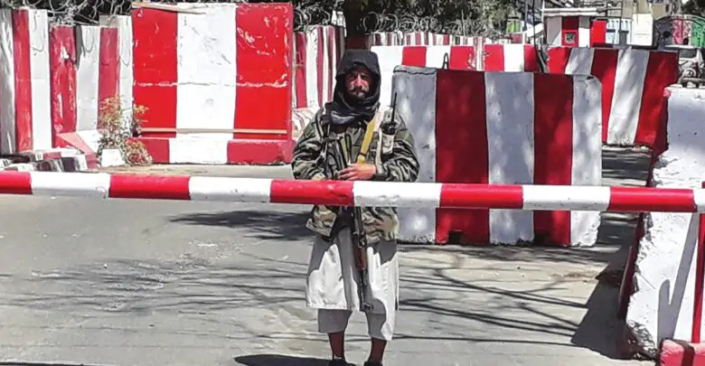 A Taliban fighter stands guard at the entrance of the police headquarters in Ghazni on August 12, 2021