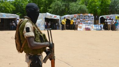A soldier stands guard near information stands in a camp in Diffa, Niger