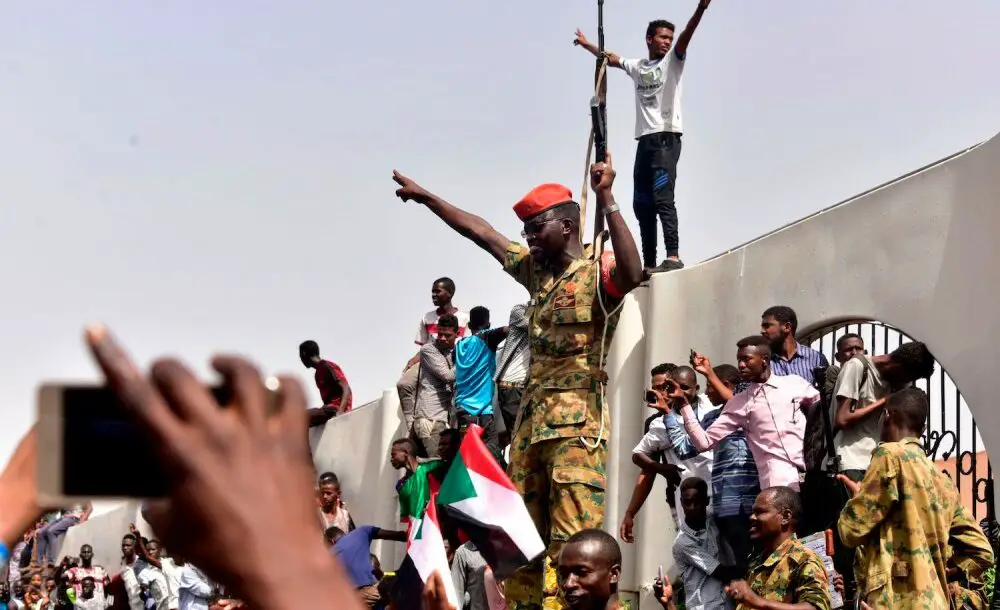 After Sudanese President Omar al-Bashir was ousted, members of the Sudanese military gather in a street with protestors in central Khartoum