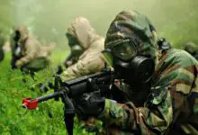 US Army soldier with the Chemical Corps points his rifle while wearing a protective gas mask.