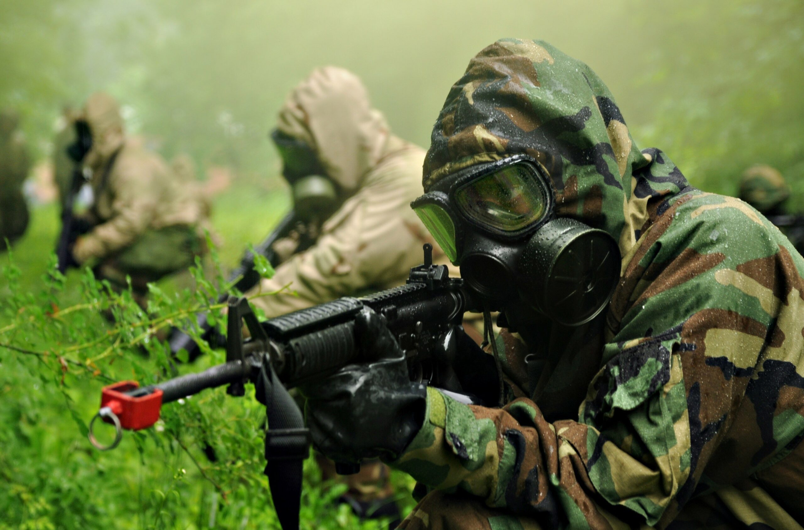 US Army soldier with the Chemical Corps points his rifle while wearing a protective gas mask.
