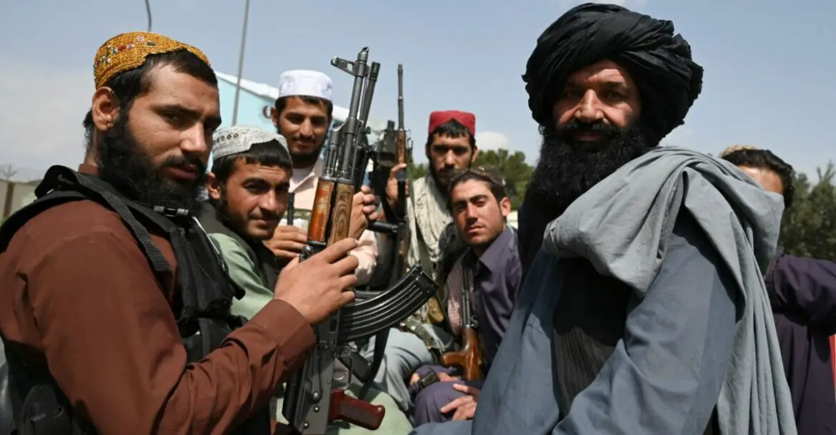 Taliban fighters sit on the back of a pick-up truck at the airport in Kabul