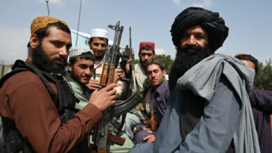 Taliban fighters sit on the back of a pick-up truck at the airport in Kabul