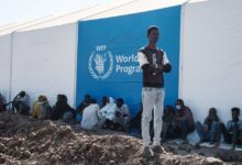 Ethiopian refugees wait for distribution of aid next to a warehouse erected by the World Food Programme at Um Raquba refugee camp in Gedaref, eastern Sudan