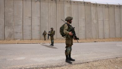 Israeli soldiers stand on guard by the fence along the border with the Gaza Strip