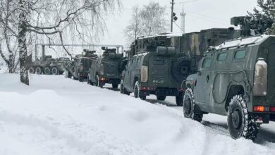 Russian military vehicles waiting to load a military cargo plane to depart to Kazakhstan