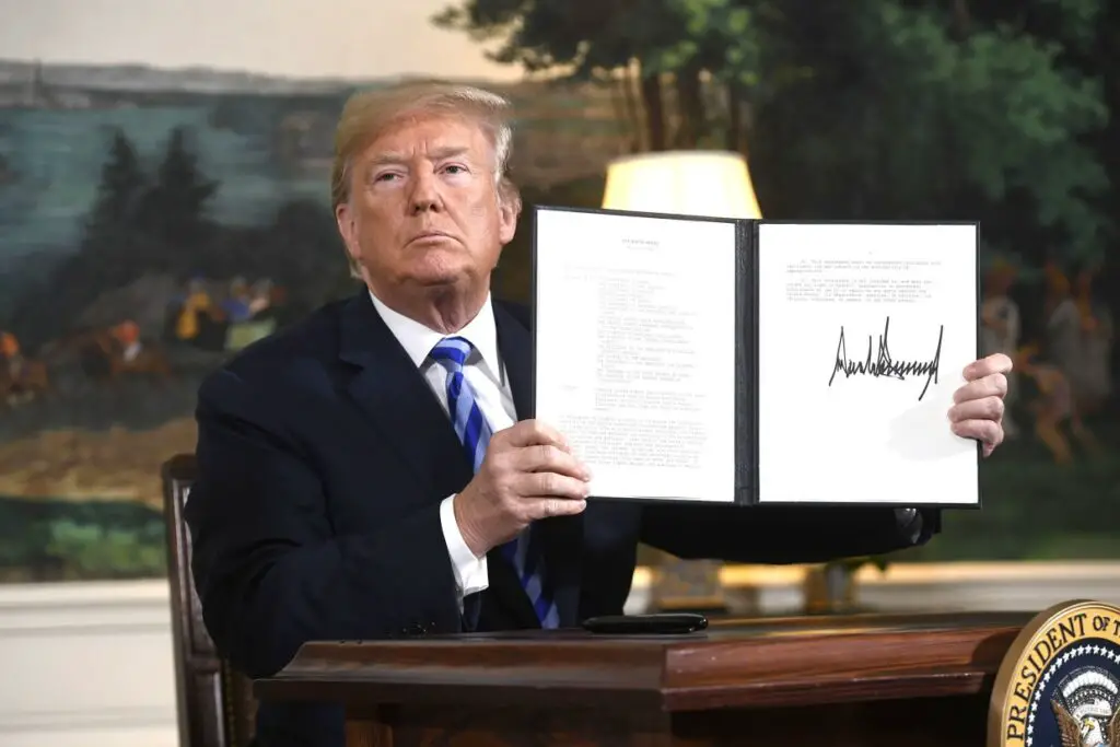 President Donald Trump signs a document reinstating sanctions against Iran
