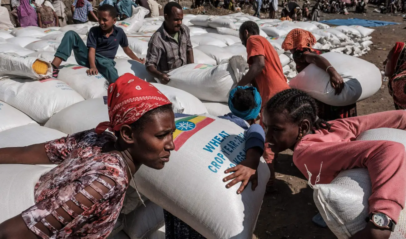 Women carry sacks of wheat during a distribution of food organized by the Ethiopian government