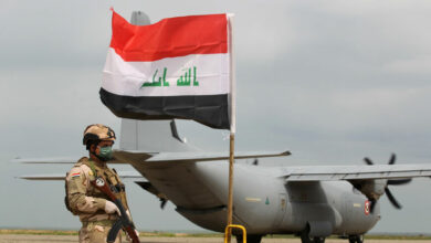 Iraqi soldier stands guard in front of a US military air carrier