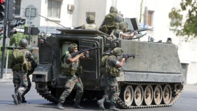 Lebanese soldiers take cover behind their armored vehicle as they enter the Abra neighborhood on the eastern outskirts of Sidon
