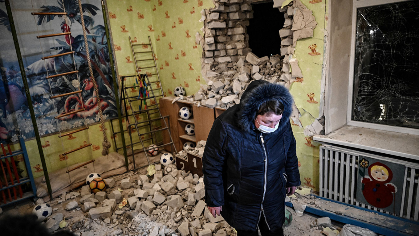 A woman stands among debris after the reported shelling of a kindergarten