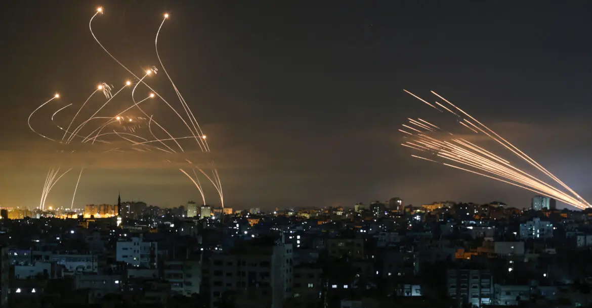 The Israeli Iron Dome missile defense system, left, intercepts rockets fired from Gaza Strip