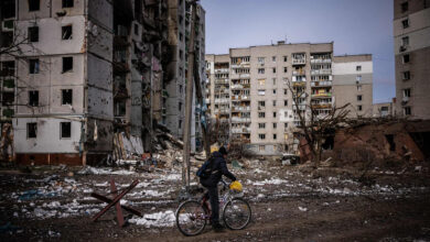 A man rides his bicycle in front of residential buildings damaged in yesterday's shelling in the city of Chernihiv