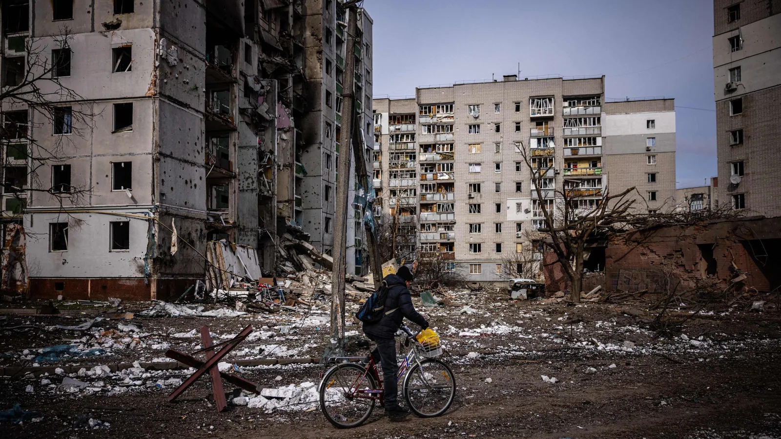 A man rides his bicycle in front of residential buildings damaged in yesterday's shelling in the city of Chernihiv