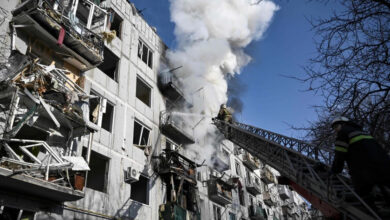Firefighters work to extinguish a blaze after a shell struck a building in the town of Chuguiv in eastern Ukraine